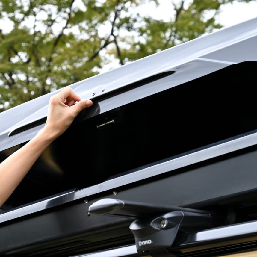 view of operson opening up the Inno BRM850BK Rooftop Cargo box installed on a vehicle