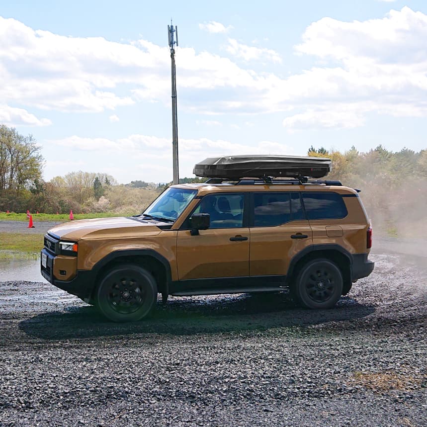 Inno BRM855BK cargo box installed on orange Toyota Highlander driving on gravel