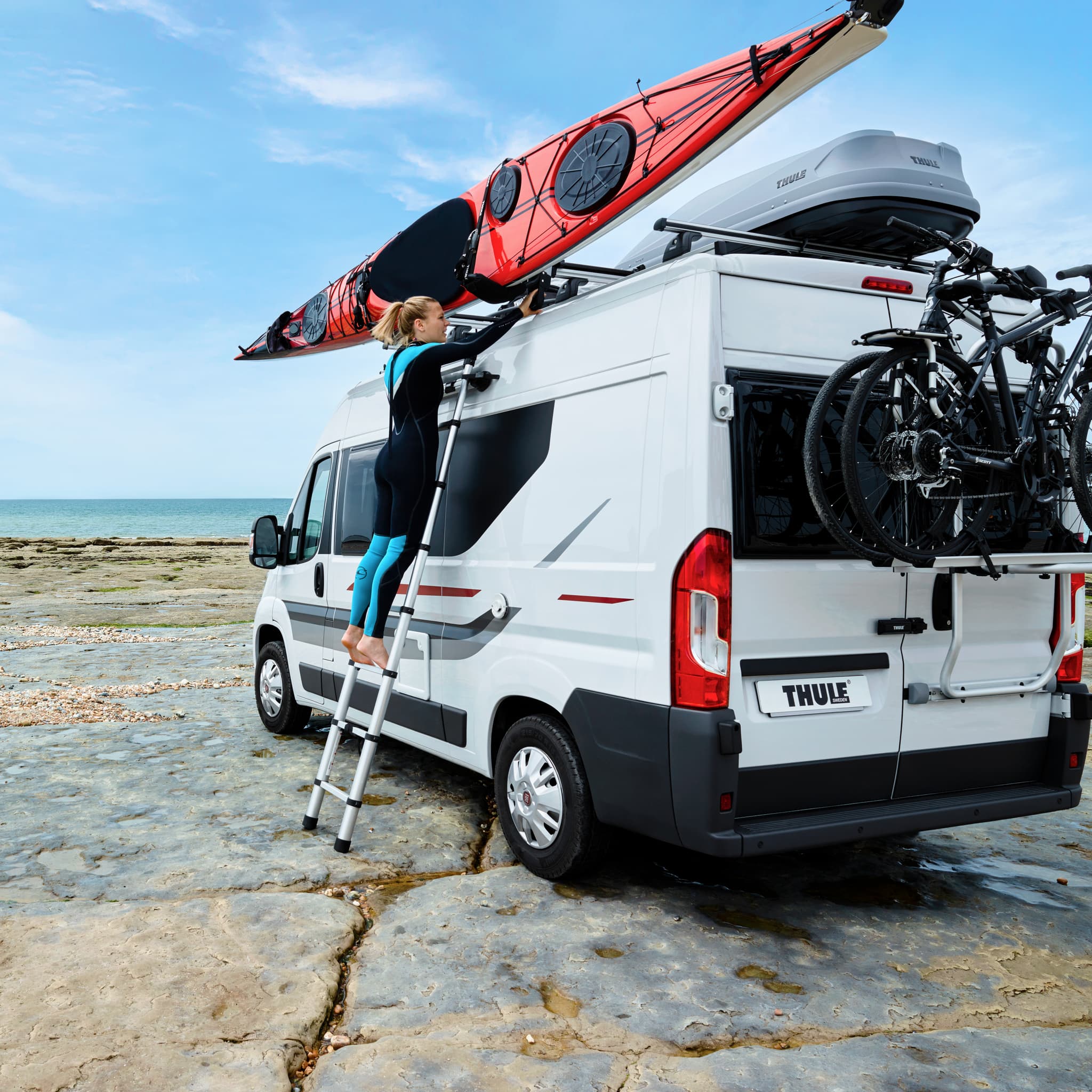 Woman climbing up Thule Telescoping Van Ladder at a beach