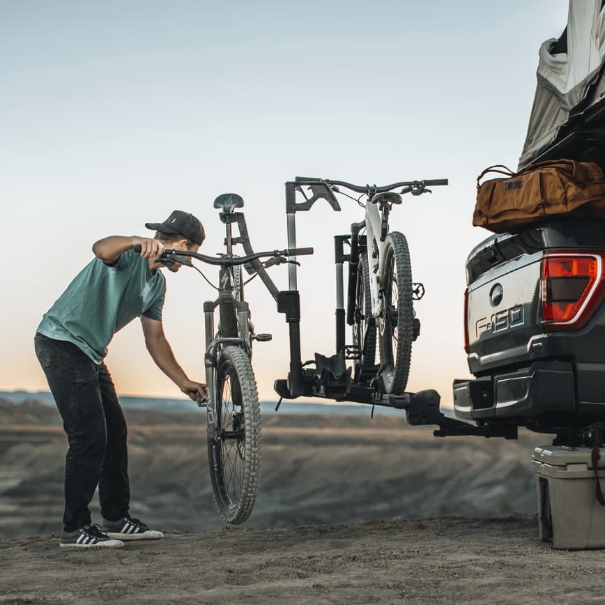 Man repairing bike that is loaded to the Thule Verse Bike Repair holder out in nature