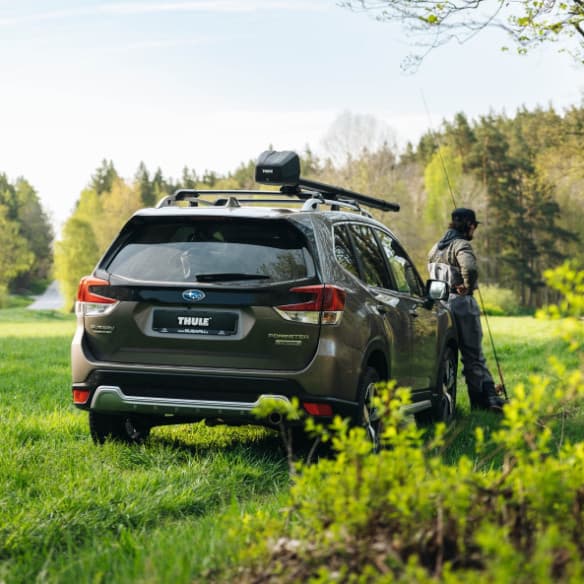 Man walking away from the SUV equipped with the Thule Rod Vault with a rod in hand