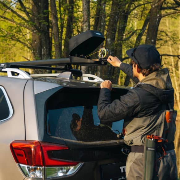 Man putting rod in the Thule Rod Vault that is installed on his SUV