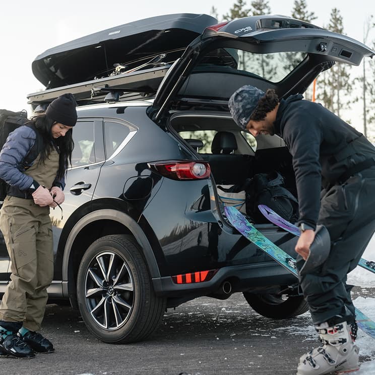 Yakima NX Skinny Cargo box open on vehicle with people setting up their skis in the photo