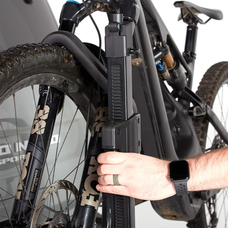 Close-up of latching system on Thule Verse bike rack. Persons hand is pulled up the latching arm on tire