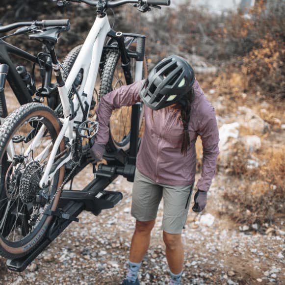 Thule Verse installed on vehicle with bikes loaded. Person unloading bikes out in nature