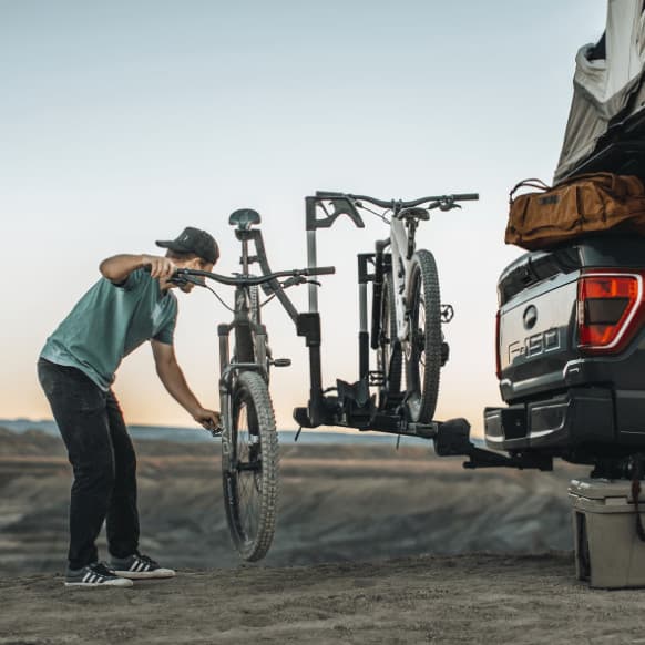 Thule Verse installed on back of F150. Person taking bike off of the bike rack out in nature