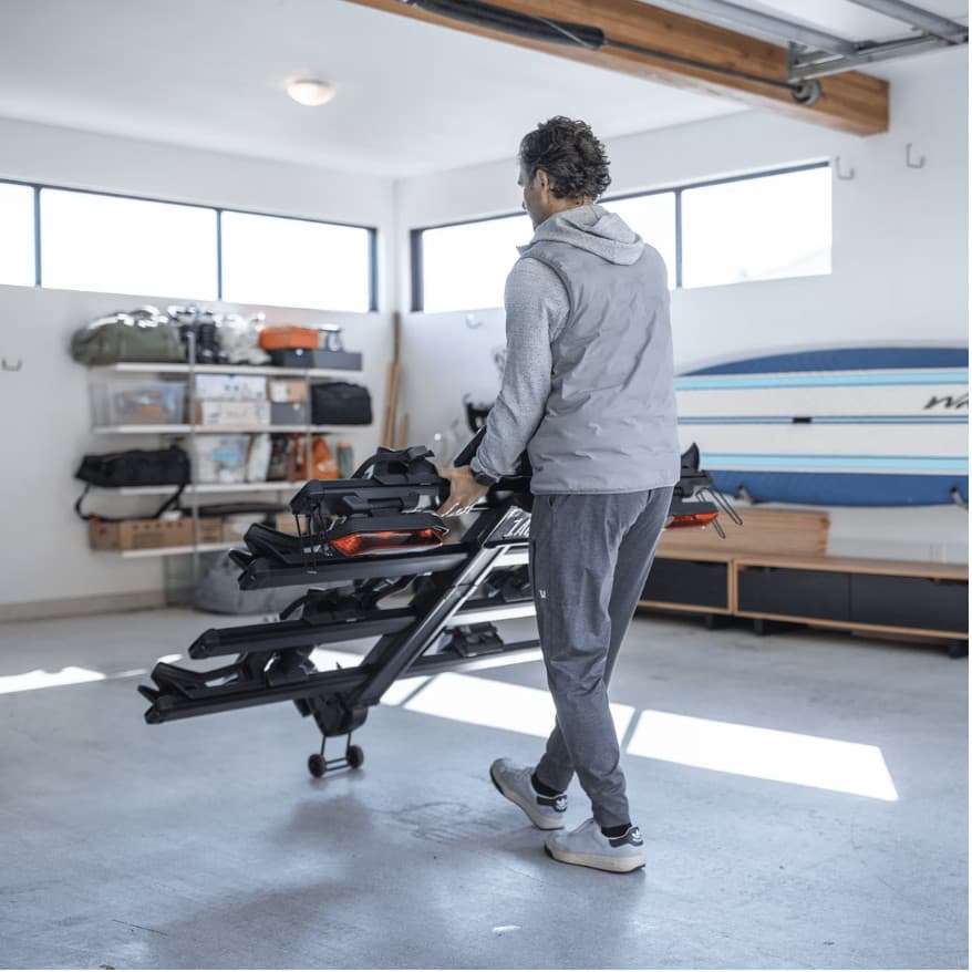 Man pulling a 4 bike rack through garage using Thule Transport Wheels